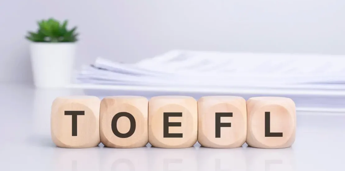 Vários cubos de madeira sobre a mesa formando a palavra TOEFL